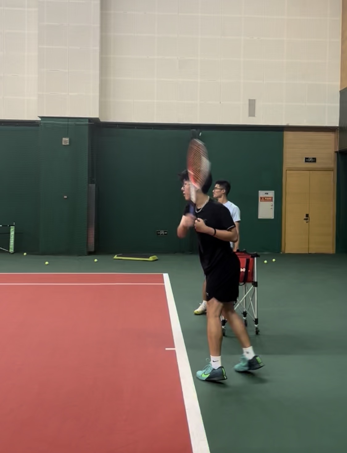 Mingze Steven Sun practicing tennis on an indoor court